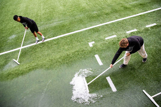 Funktionärer skrapar bort vatten från planen