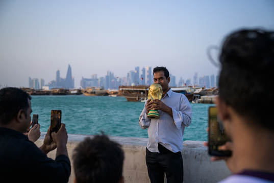 A man poses with a trophy replica at the Corniche Promenade
