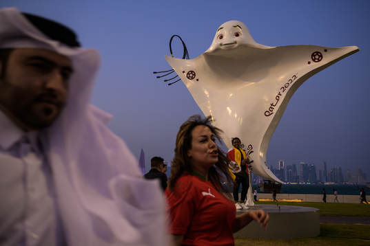 People walk past the mascot La'eeb