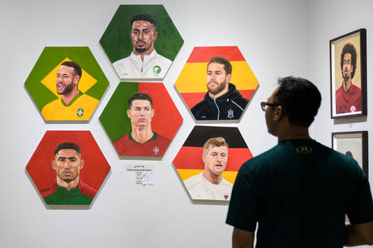 A man watches paintings of football stars