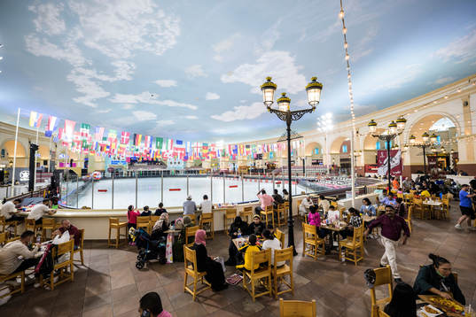 People dine next to an indoor ice skating rink at Villaggio Mall