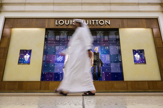 A man walks past a Louis Vuitton store at Villaggio Mall