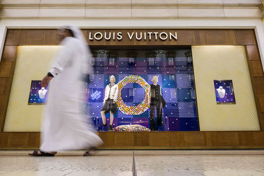 A man walks past a Louis Vuitton store at Villaggio Mall
