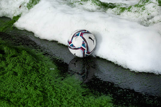 En boll mellan en hög med gummigranulat och en snöhög