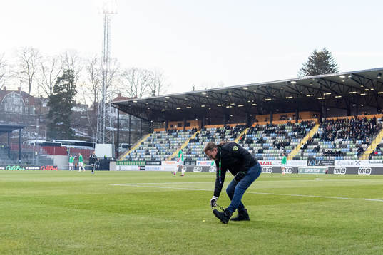 En funktionär plockar skärp från planen