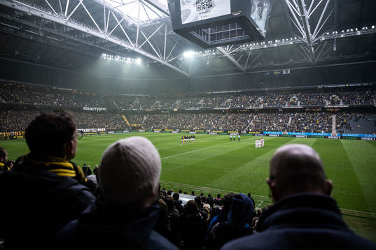 Vy från läktaren när AIKs och Sirius spelare står uppställda för en tyst minut