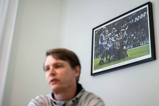 Ett fotografi på jublande spelare på väggen bakom IFK