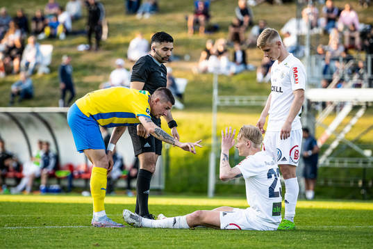 Eskilsminne IFs André Reinholdsson och domare George Jansizian tittar till Ängelholms Filip Örnblom som har skadat sig