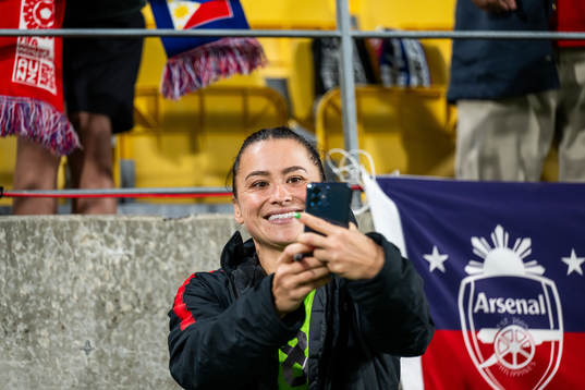 Ali Riley of New Zealand takes pictures with spectators