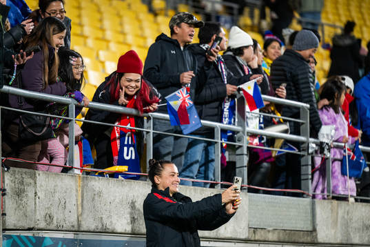Ali Riley of New Zealand takes pictures with spectators