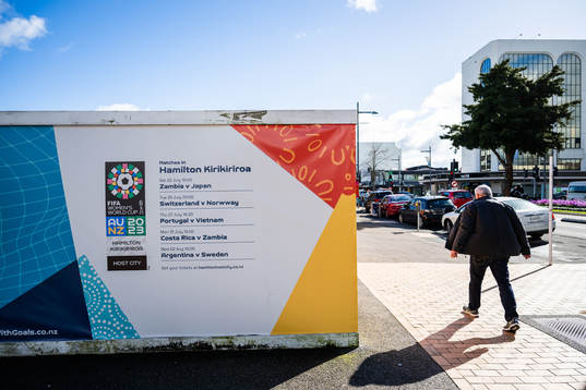 A man walks past barriers with the logo for the FIFA Women's World Cup