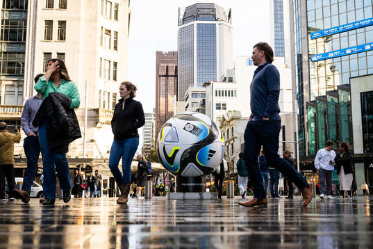 People walk past a replica of the official match ball