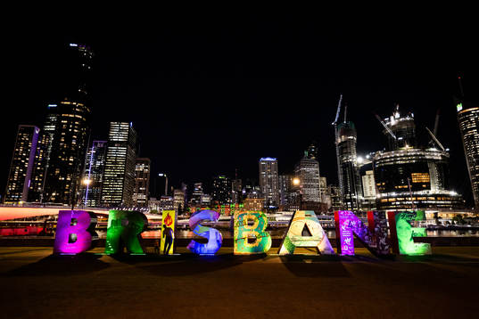 Lit up letters that read ”Brisbane”  is seen in front of the city skyline