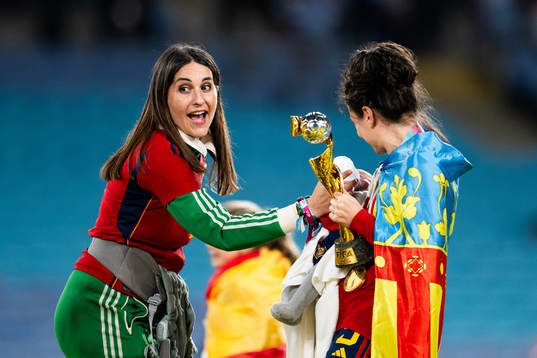 Ivana Andres of Spain holds a child that is being bottle fed as she poses for a photo with the trophy