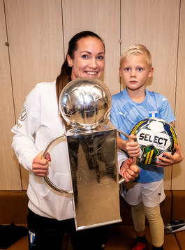 Malmö FFs läkare Amanda Lahti med familj poserar för en bild med Lennart Johanssons pokal i omklädningsrummet för att fira SM-guldet