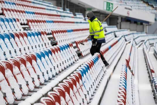 Snow at the seats as a worker walks past at Ullevi stadium