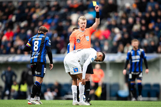 Domare Adam Ladebäck delar ut ett gult kort till Halmstads Amir Al-Ammari