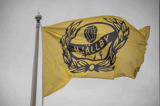 Flagga med Mjällbys logotype på