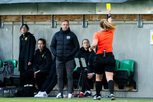 Domare Sandra Almkvist delar ut ett gult kort till Hammarbys tränare Martin Sjögren