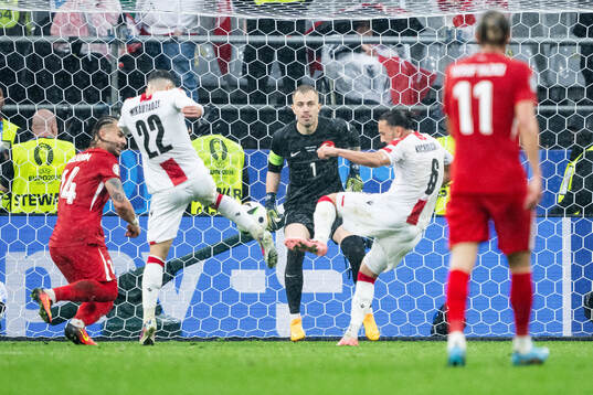 Georges Mikautadze and Giorgi Kochorashvili of Georgia against goalkeeper Mert Gunok of Türkiye