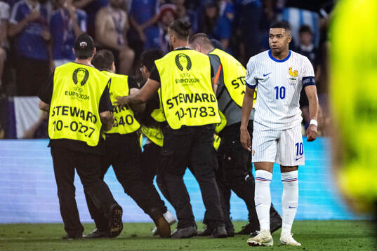 Stewards take care of a pitch invader next to Kylian
