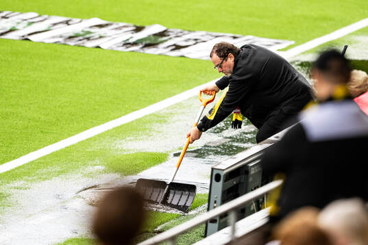 Elfsborgs ordförande Sune Lundqvist hjälper till att skyffla undan vattnet på Borås arena