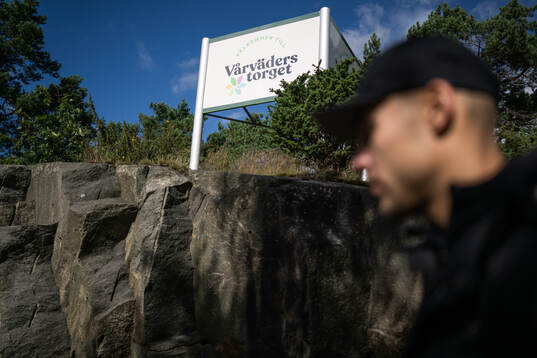 Häckens Ali Youssef går förbi en skylt med texten Vårväderstorget
