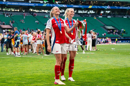Frida Maanum and Stina Blackstenius of Arsenal celebrate with the trophy
