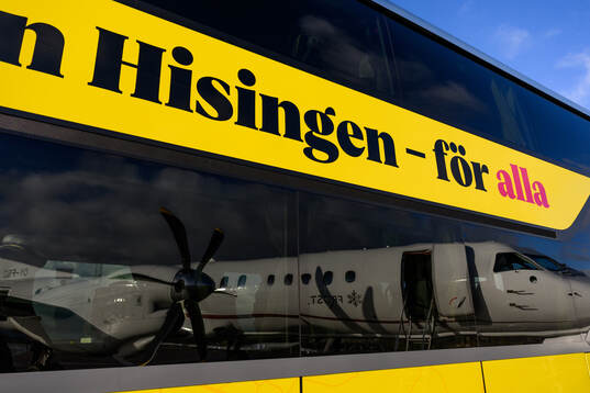 The reflection of an airplane in the windows of a bus