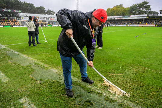 Funktionärer skrapar bort vatten från planen