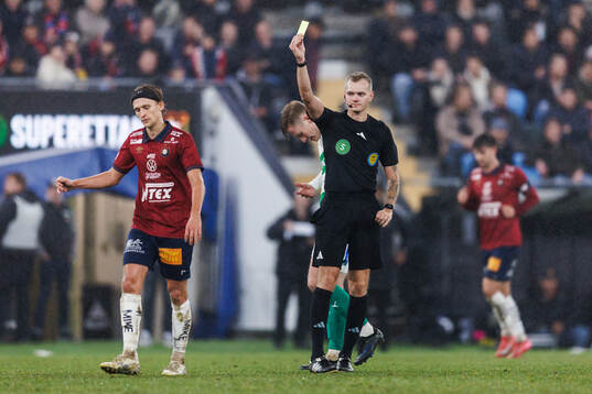 Domare Fredrik Alknäs delar ut ett gult kort till