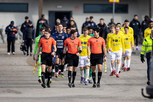 Domare och spelare på väg till planen